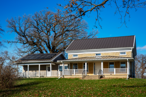 Tan two story farm house with white fence